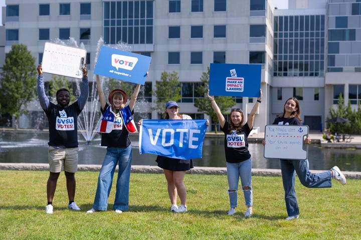 5 Students holding GVSU Votes signs